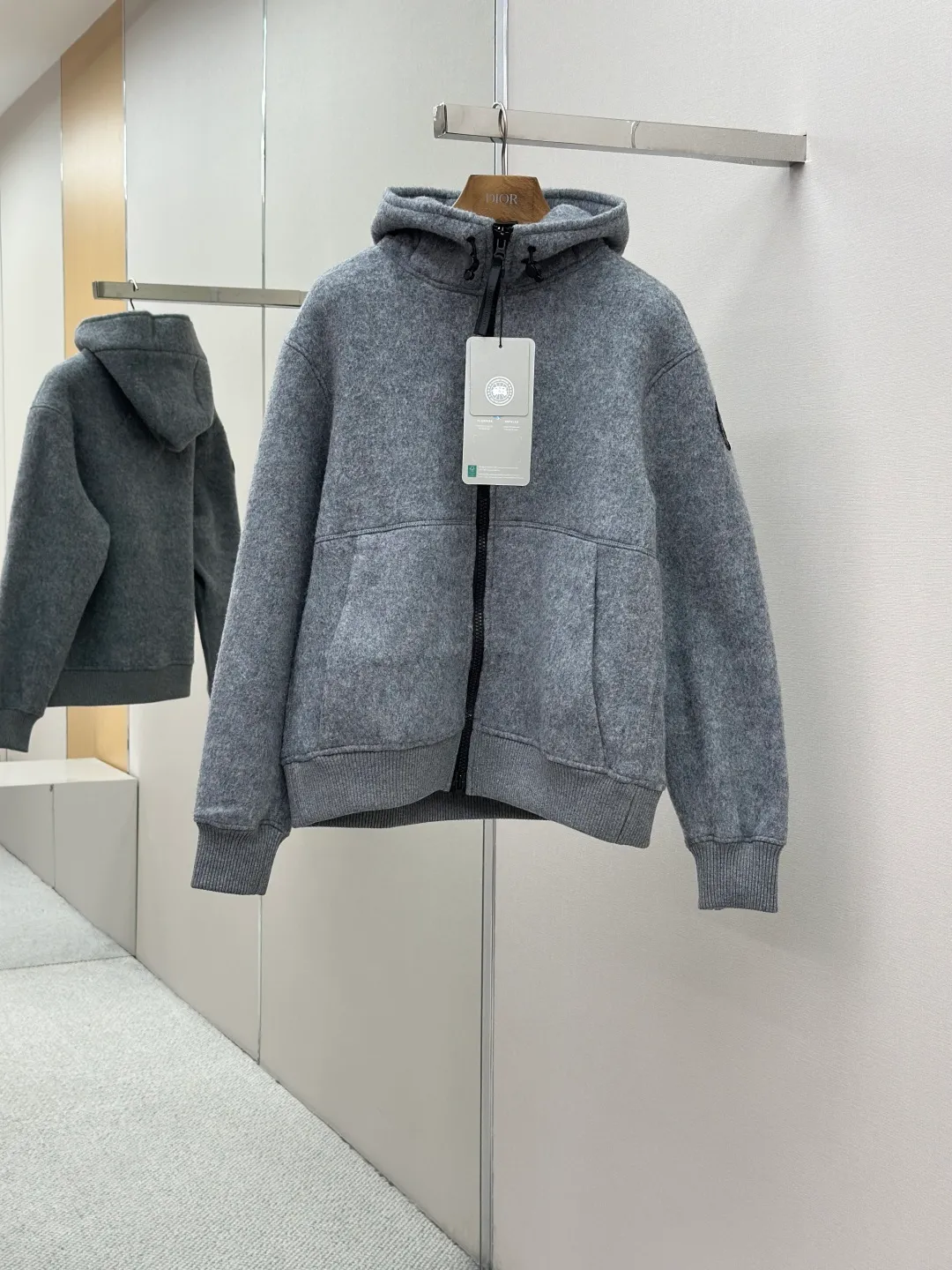P800 ￼ Canada Goose Fleece Badge Hooded Jacket Fabric selection: Wool fleece fabric blended with wool as the main body and a very small amount of spandex and polyester fiber. Wool is a core natural ingredient that provides unparalleled temperature regulation, antibacterial and anti-odor properties and a skin-friendly feel. The feeding of a small amount of spandex gives the fabric a certain degree of four-way elasticity, making it non-restrictive during daily activities. As the basis of fleece's structure, polyester fiber enhances the fabric's durability, wrinkle resistance and quick-drying properties. It contributes to the loft of the fleece and provides functions such as trapping air.  Detail 1: The sleeves and hem are closed with 2×2 ribbing. Its strong elasticity can closely fit wrists and waists of different thicknesses, forming an effective 'seal' to prevent cold wind from blowing back. It can still maintain its original shape after repeated stretching and use, and is not easy to loose and deform. And the ribbed cuffs can convey a sense of design and enhance the visual beauty.  Detail 2: The combination of hood design and elastic buckle improves warmth and windproof performance when wearing.  Accessories: Customized elastic drawstring buckle Customized zipper pendant Customized armband SIZE: S M L XL